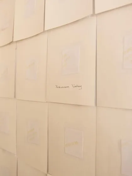 A close-up of the "Directory of the Outsiders" installation, where stories are subtly printed on paper. The work invites quiet contemplation on themes of exclusion and memory.