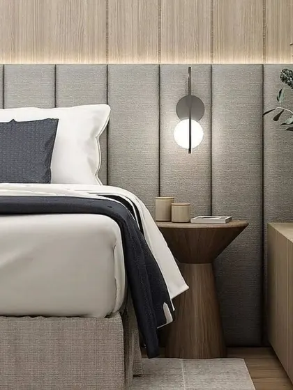 A close-up of a bedside table in a modern bedroom, showing the combination of wood, fabric, and stylish lighting.