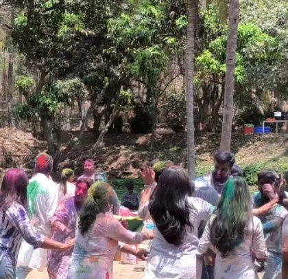 Guests enjoying the celebration, dancing together in a circle, covered in festive colors. We focus on creating moments of connection and fun.