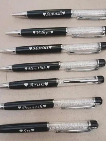 A batch of personalized crystal pens, each engraved with a name and a small heart. These make for beautiful and elegant gifts.