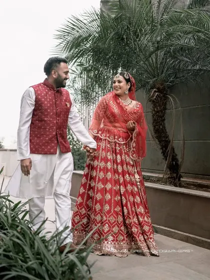 A candid moment of a walk together, filled with smiles. The coordinated red in their outfits adds a lovely pop of color to this happy, natural wedding portrait.