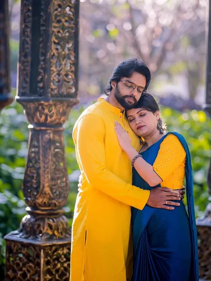 An intimate and heartfelt embrace between two ornate pillars. The soft light and the couple's tender pose make this a beautifully emotional portrait in ethnic wear.