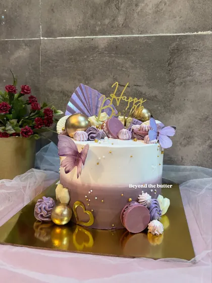 Turning a dream cake into reality with this purple and white creation. It's lavishly decorated with macarons, chocolate spheres, and butterflies for a truly luxurious feel.