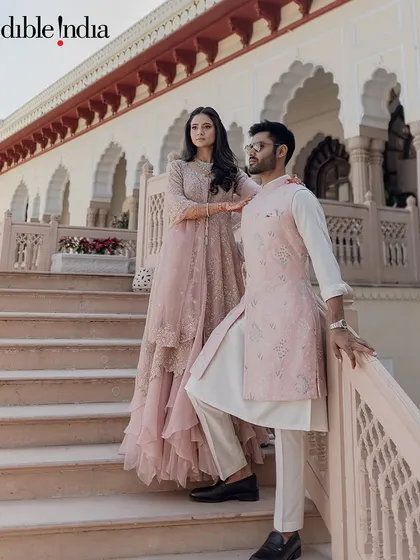 A couple poses on the steps of a Jaipur palace, their pastel outfits complementing the building's architecture.