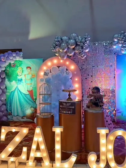A close-up of the stage details, including a shimmer wall, themed backdrops, and decorative props like birdcages.