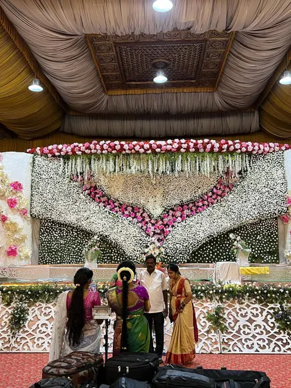 A massive floral heart-shaped backdrop for a wedding reception. This design uses a dense arrangement of white and pink flowers to create a romantic and visually stunning focal point for the couple.