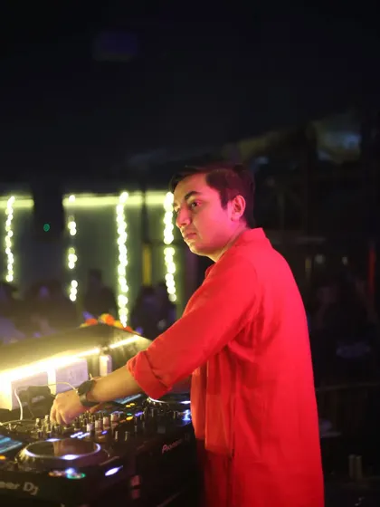 A side profile of me at the console during a Diwali party, surrounded by festive lights. I'm always in control of the music and the mood.