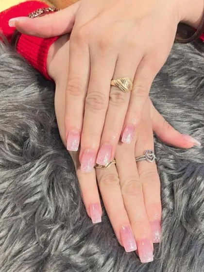 A very subtle and shimmery pink ombré effect on long square nails, giving a 'your nails but better' look with a hint of sparkle.