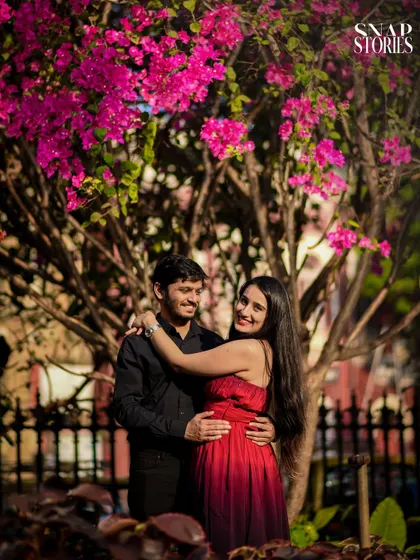 A vibrant portrait of a couple framed by beautiful pink bougainvillea flowers, adding a pop of color and natural beauty to their pre-wedding shoot.
