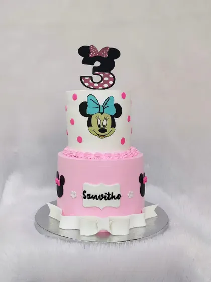 A classic two-tier Minnie Mouse cake. I used a polka dot pattern, a fondant bow, and character toppers to create this timeless design for a third birthday.