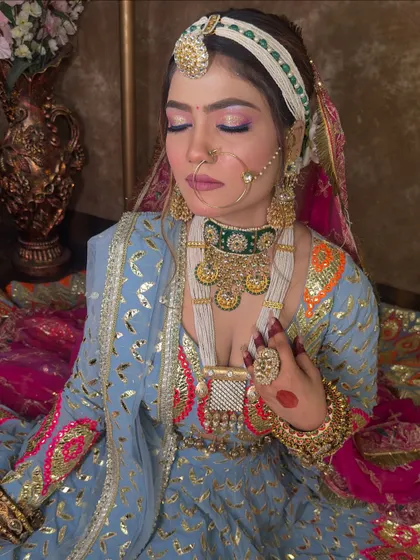 A close-up on the jewellery for the blue lehenga look. The combination of a green beaded choker with a long white beaded necklace adds layers of texture and color, complementing the outfit's embroidery.
