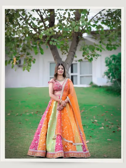 A beautiful full-length portrait of the bride-to-be during her pre-wedding shoot. Her vibrant, multi-colored lehenga stands out against the green lawn, showcasing her unique style.