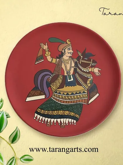 This wooden wall plate features a kingly figure on horseback, painted in a style reminiscent of Indian miniature paintings. The rich red background makes the artwork pop, creating a striking visual.