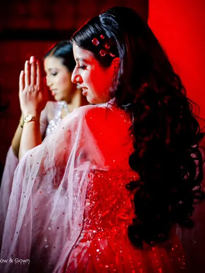 An artistic shot of the bride-to-be looking at her reflection. The dramatic red lighting creates a bold and glamorous mood for this engagement portrait.