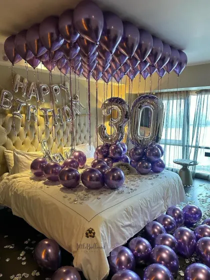 A sophisticated 30th birthday setup in a deep purple and silver color scheme. The metallic balloons add a touch of glamour, creating a mature and celebratory atmosphere in this hotel room decoration.
