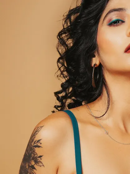 This shot frames the model's shoulder, highlighting her floral tattoo and the delicate necklace, combining beauty with personal style.