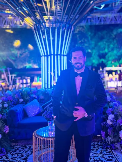 A moment of calm before the storm of a grand Sangeet night, standing before a beautifully lit and decorated venue.