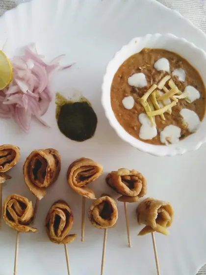 A creative presentation of dal makhani with whole wheat paratha lollipops, served with green chutney and pickled onions.