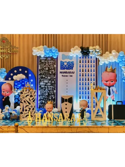 A detailed Boss Baby theme for a first birthday, featuring multiple backdrops, character cutouts, and themed props like a briefcase and a tuxedo-print plinth.