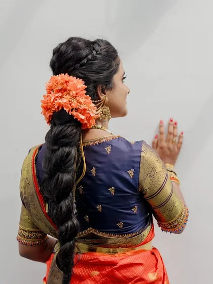 A view from the back, showing the bride's intricate hairstyle and the simple yet elegant embroidery on her navy blue blouse.