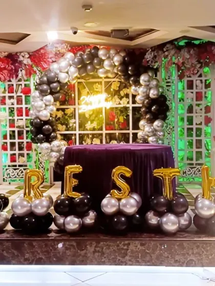 A stylish Boss Baby themed stage decoration with black and silver balloons and marquee letters.
