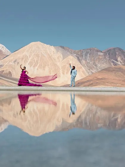 The serene beauty of Leh, where the mountains meet their perfect reflection. This shot captures a quiet, epic moment, with the vibrant purple gown creating a stunning contrast against the tranquil blues and earthy tones of Pangong Lake.