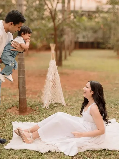 A wider shot of the family playing, showing the beautiful park setting and the lace teepee prop.