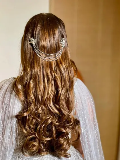 A half-up style with soft waves, featuring a beautiful crystal and chain accessory at the back.