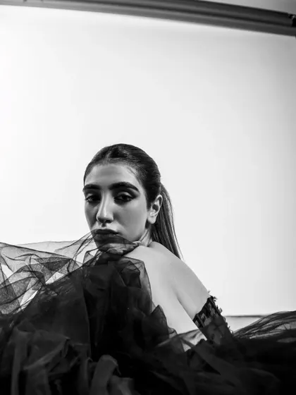 A close-up monochrome shot that uses the gown's fabric to frame the model's face, creating an intimate and high-fashion portrait.