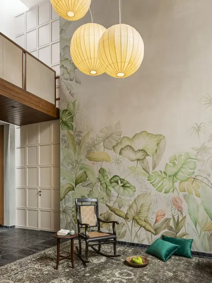 Another view of the living area, where a rocking chair sits before the large foliage mural. This corner is designed as a quiet space for reflection, connecting with the home's artistic and natural themes.