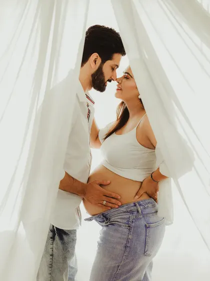 An intimate and romantic portrait of the couple, framed by sheer white curtains. The soft light and their close embrace create a dreamy and beautiful image.