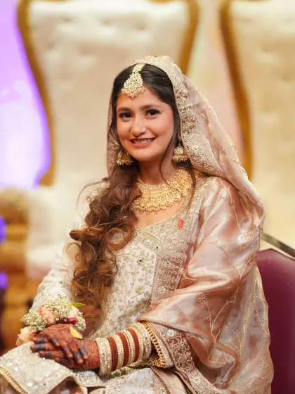 A seated portrait of the bride, looking serene and happy. The soft lighting beautifully illuminates her features and elegant attire.