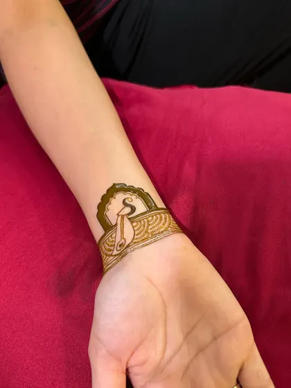 Personalizing henna with initials is a classic for a reason. Here, the groom's initial 'S' is designed with a peacock feather.