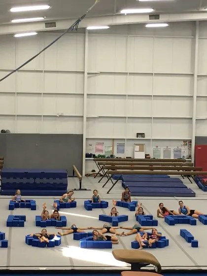 Our gym is a giant playground built for fun and fitness! Here, our gymnasts take a creative break, using foam blocks to spell out a New Year's greeting. We believe in working hard and playing hard.