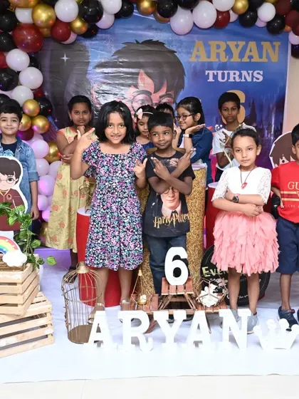 A magical Harry Potter theme for a 6th birthday. The kids are having a great time posing in front of the decor, which includes a custom backdrop and character cutouts.