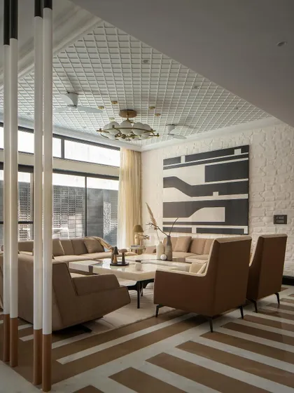 The formal living area showcases a fusion of Indian marble and brick flooring, unified by a monochromatic palette. The design creates a comfortable sanctuary suited for the extreme North Indian climate.