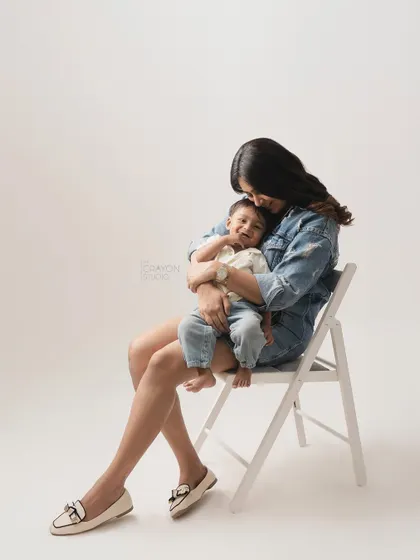 A mother sits and cuddles her son, who is smiling contentedly in her arms. A simple, beautiful portrait of their bond.