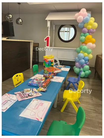 A kids' activity table set up with coloring materials and games for a rainbow-themed birthday party.
