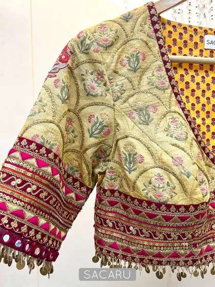 An artistic expression through fabric and embellishment. This vibrant patchwork blouse combines different prints and is finished with intricate hand embroidery using brass sequins and mirror work.