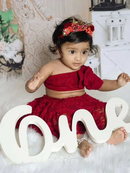 This little girl sits beside a "One" sign, marking her very special first birthday milestone.
