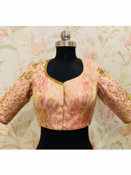 The front view of the pink floral and bird embroidered blouse, showing the elegant neckline and detailed sleeves.