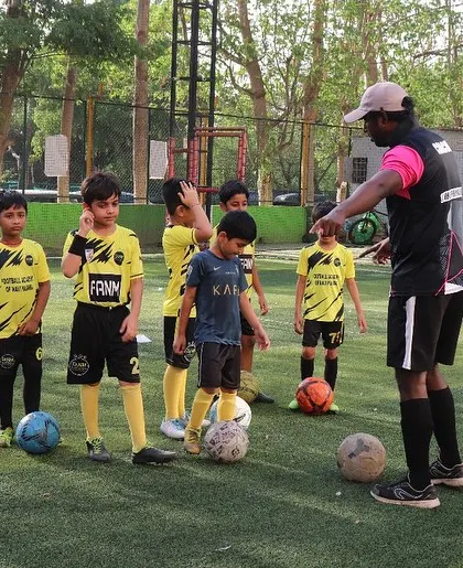 A coach huddles with a group of young players to explain a drill. Team talks are important for building unity and understanding.