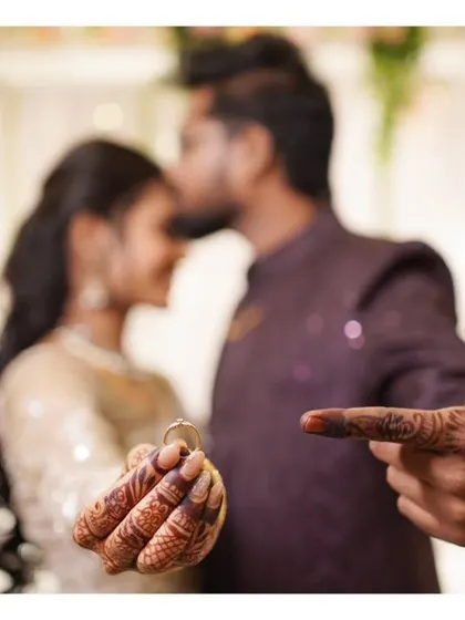 A clever engagement photo, with the groom pointing to the ring on the bride's hand.