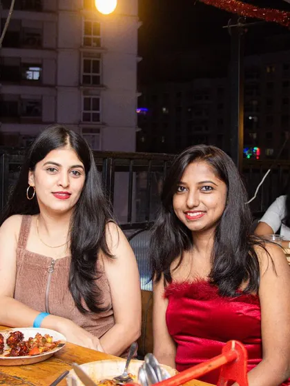 Bright smiles and good company. Two guests enjoying their time on the rooftop, with plates of delicious food in front of them.