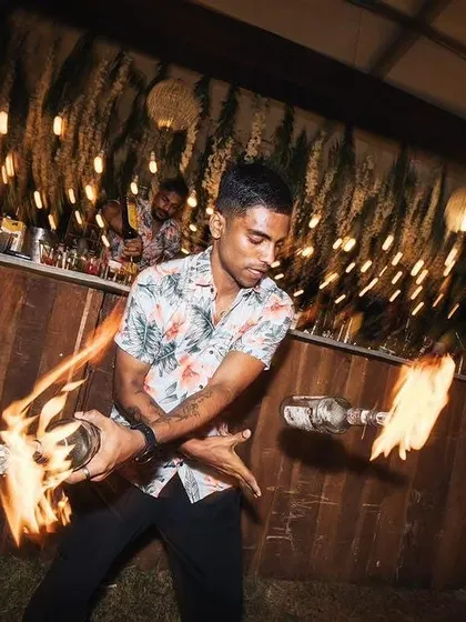 With motion and fire, our bartender creates a blur of excitement. This dynamic shot captures the energy and artistry of our flair bartending service at a rustic-themed event.