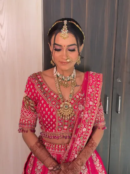 This bride's complete look, showcasing her beautiful makeup, traditional jewellery, and the rich embroidery of her wedding lehenga.