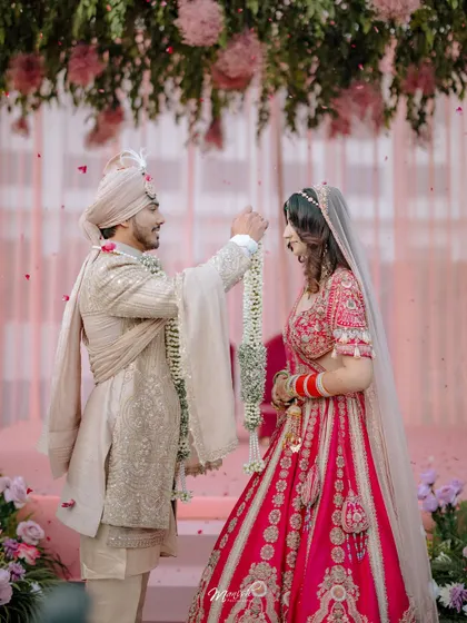 The Varmala exchange, a pivotal moment in a Hindu wedding, captured with a focus on the couple's expressions and the beautiful floral decor.
