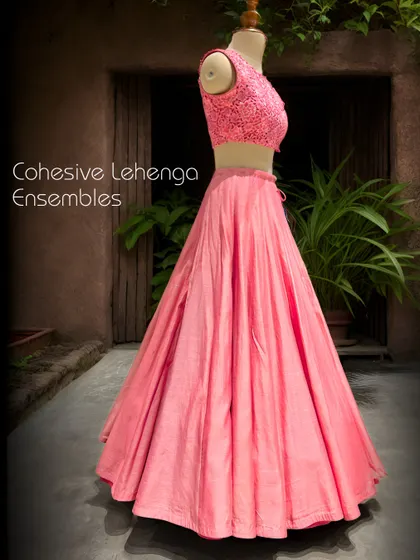 This cohesive lehenga ensemble in a vibrant pink features a raw silk skirt and a detailed cutwork blouse, creating a look of modern elegance.