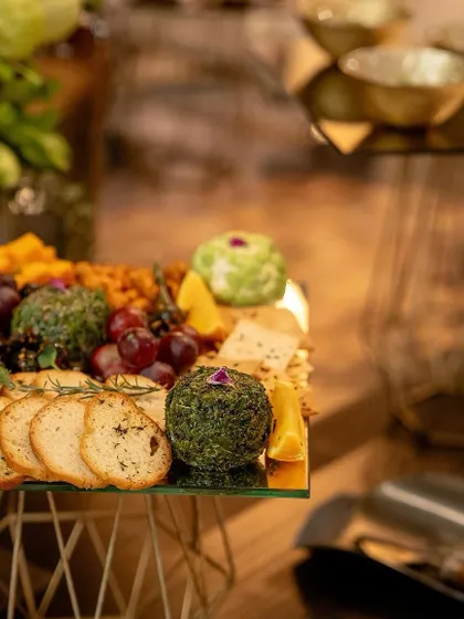 A close-up of our artisanal cheese balls, one coated in herbs and another in nuts, part of the elaborate cheese board.