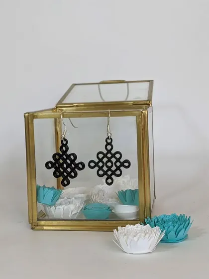 A pair of beautiful 3D printed earrings displayed in a glass box. Our workshops teach you how to design and print your own custom jewelry.